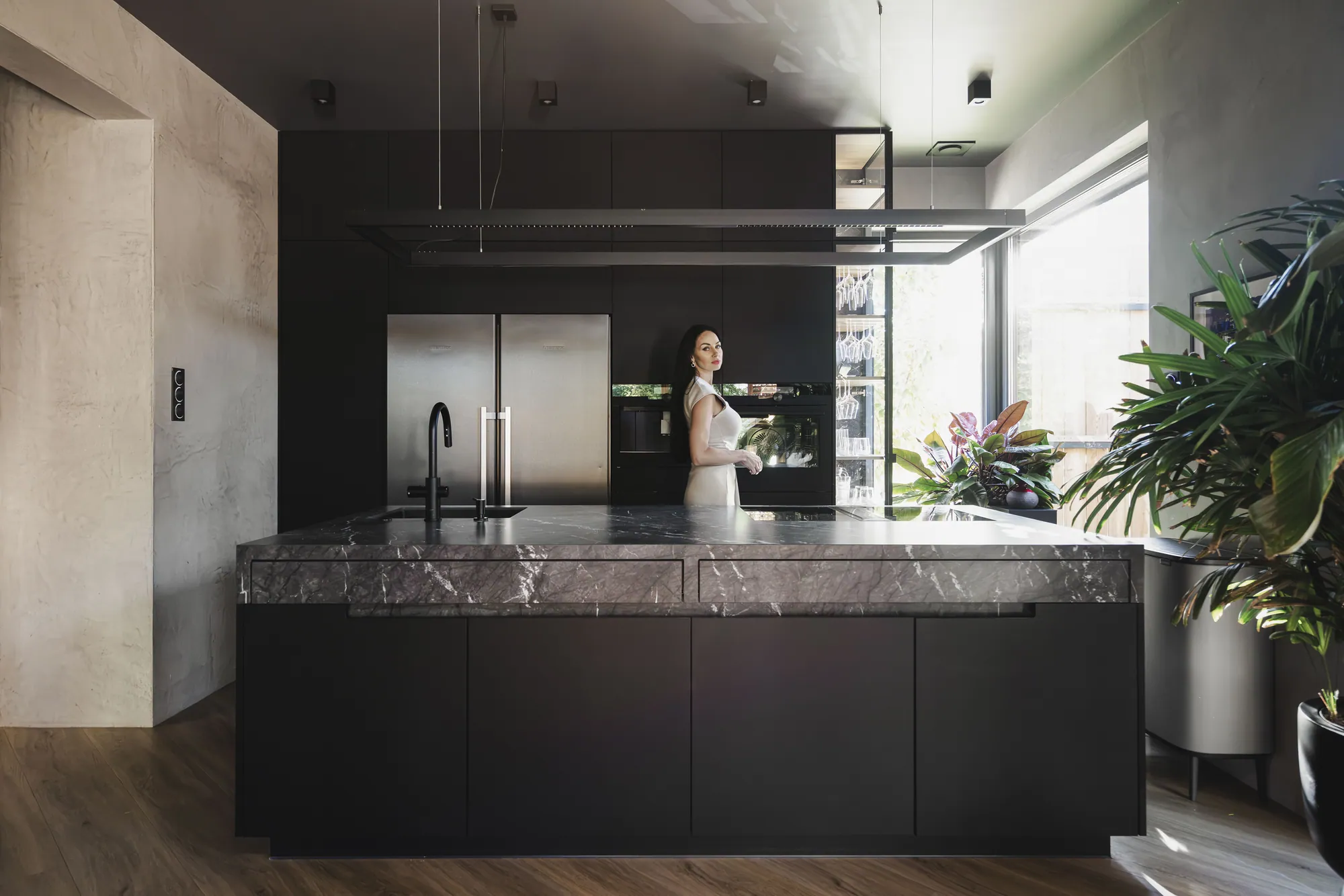 Czarna kuchnia na wymiar z wyspą ze spieku kwarcowego i lampą liniową – realizacja KUHNE STUDIO we Wrocławiu
