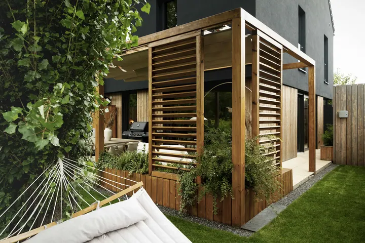 Pergola z lamelami i hamakiem w zielonym ogrodzie